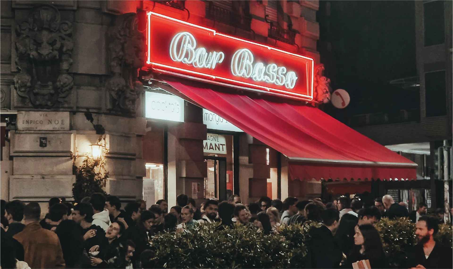 Aperitivo atmosphere at Bar Basso, Milan, with cocktails on tables and guests conversing in a lively interior.